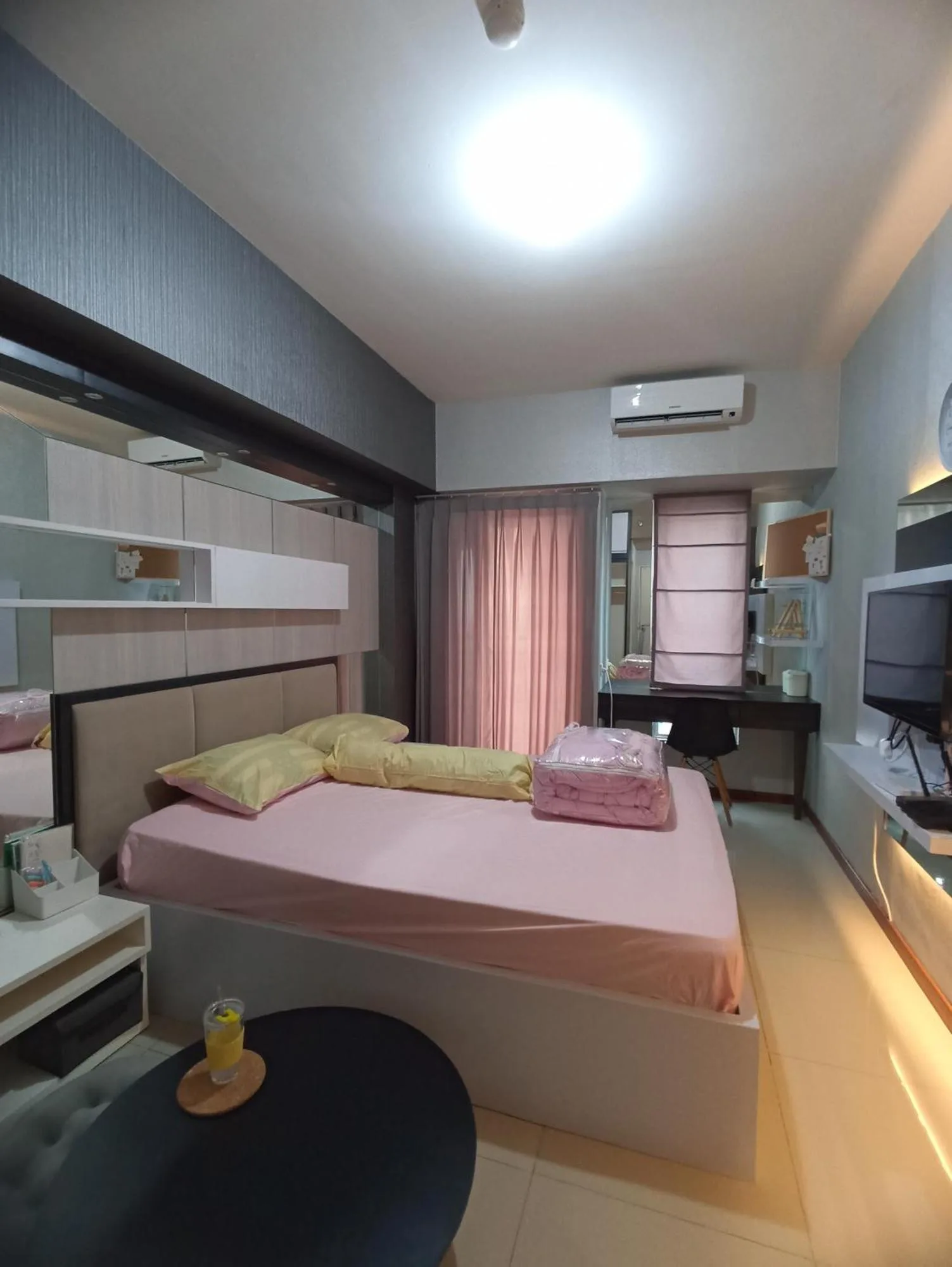 Gatotkaca Hotels Surabaya bedroom suite with pink bedding, work desk, and wall-mounted TV