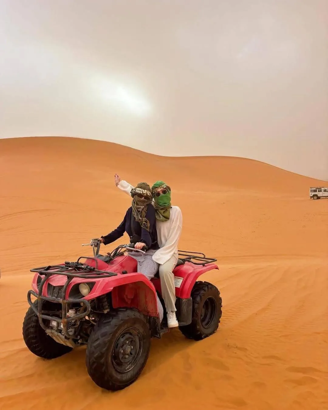 Des clients à bord d’un quad rouge dans les dunes près de Glamping Under Stars à Merzouga pendant une aventure dans le désert.