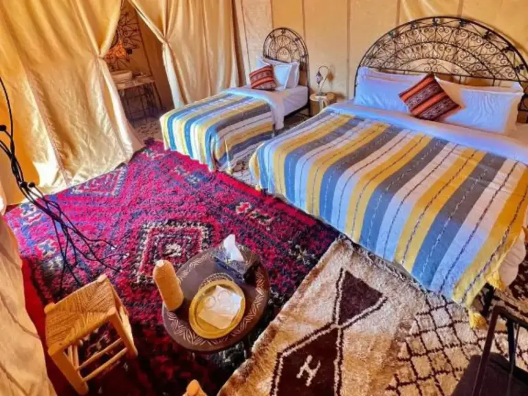 Global Luxury Camp in Merzouga twin bedroom with striped bedspreads and patterned carpets