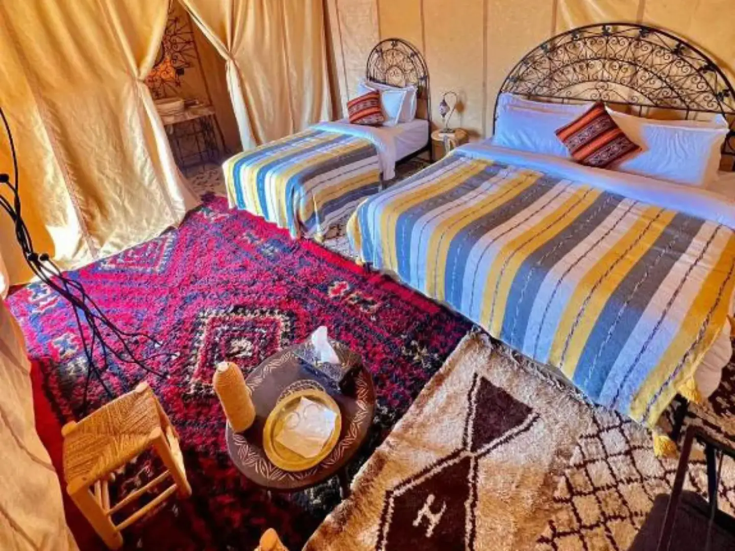 Global Luxury Camp in Merzouga twin bedroom with striped bedspreads and patterned carpets