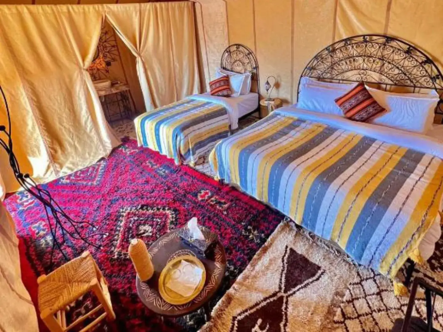Global Luxury Camp in Merzouga twin tent room with colorful rugs and bedside decor