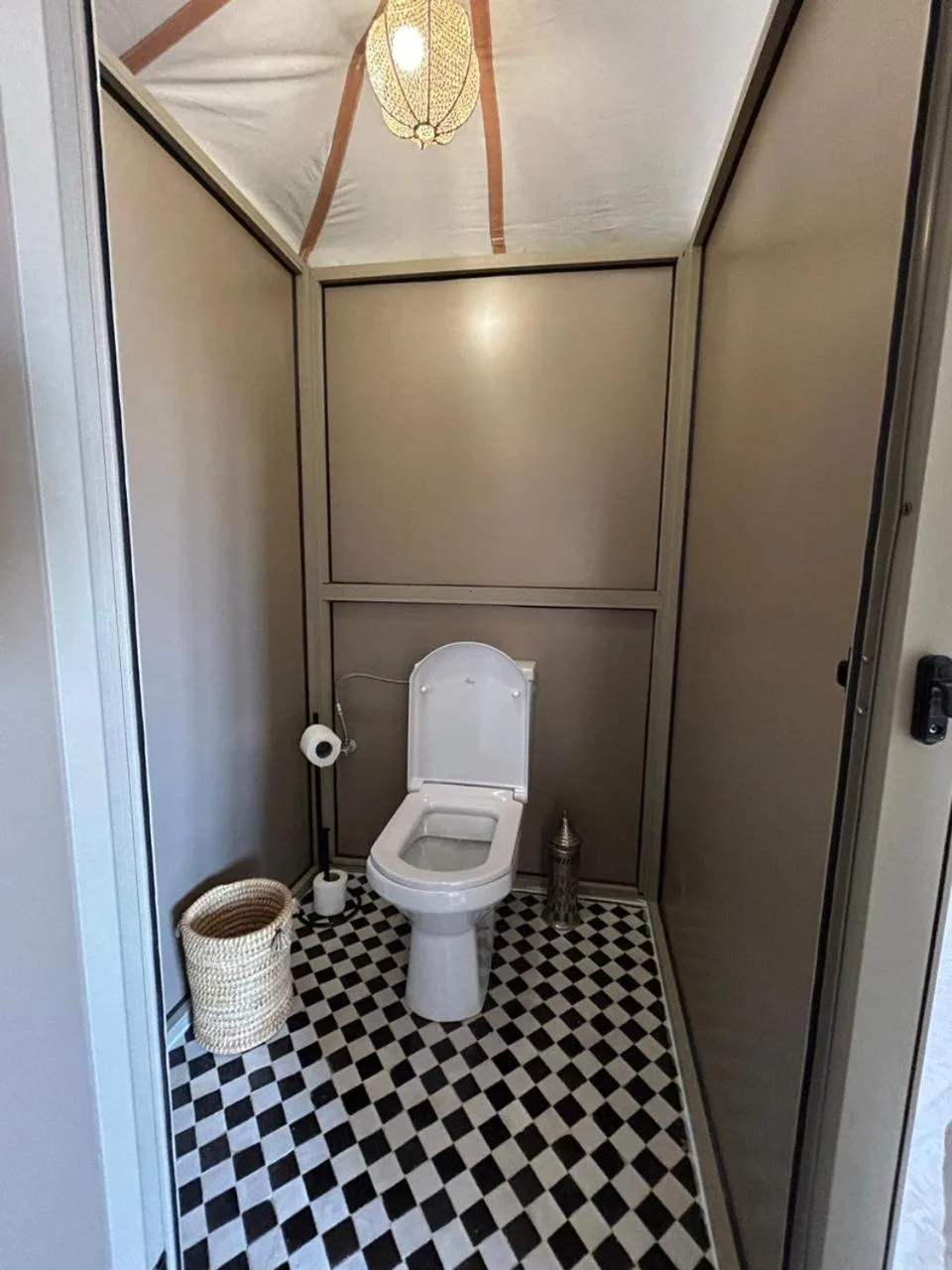 Bathroom at Golden Dunes Luxury Camp in Merzouga with a toilet, black-and-white floor tiles, and simple amenities.