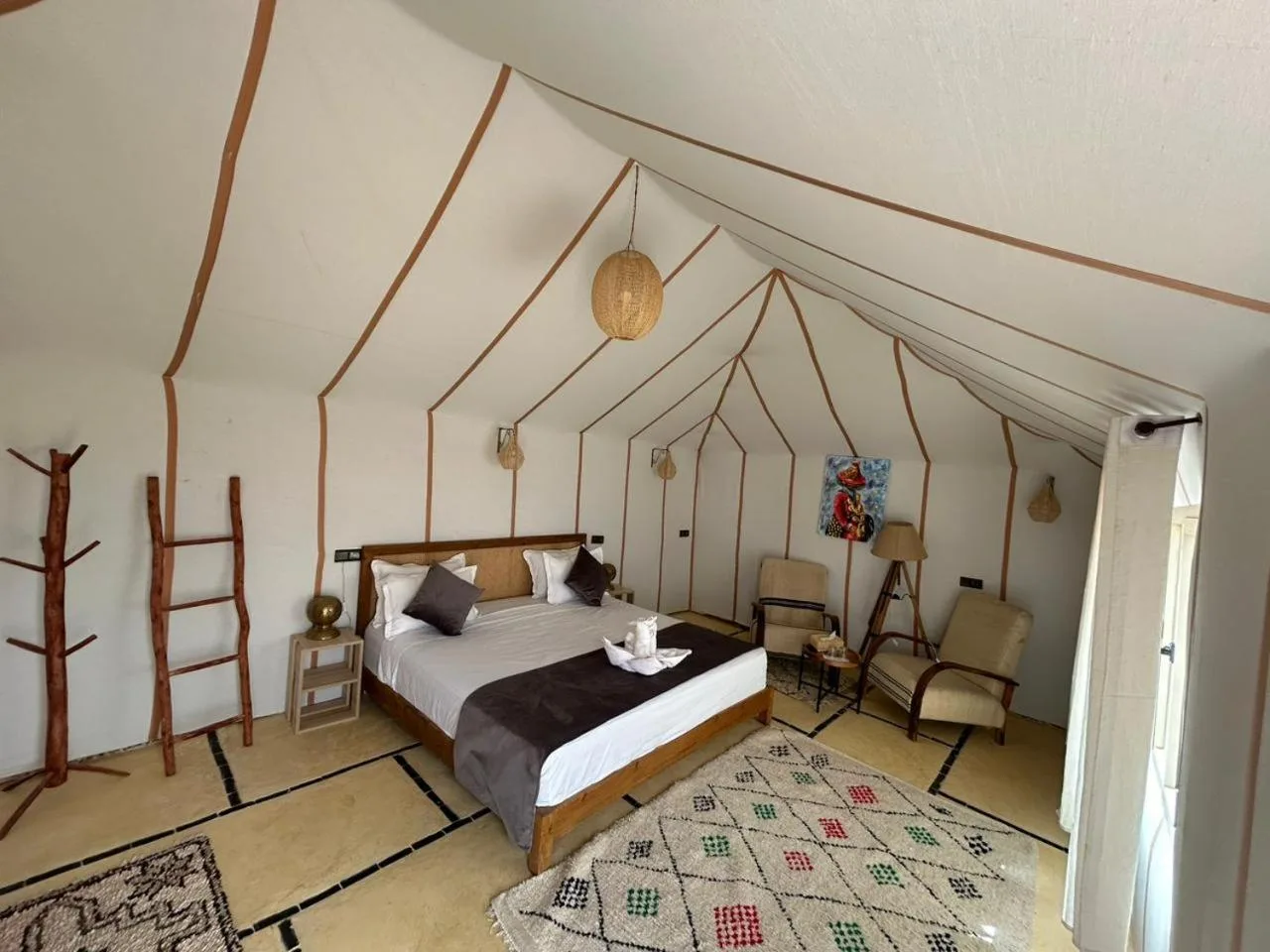 Deluxe tent suite at Golden Dunes Luxury Camp in Merzouga with a large bed, seating area, and minimalist desert style.