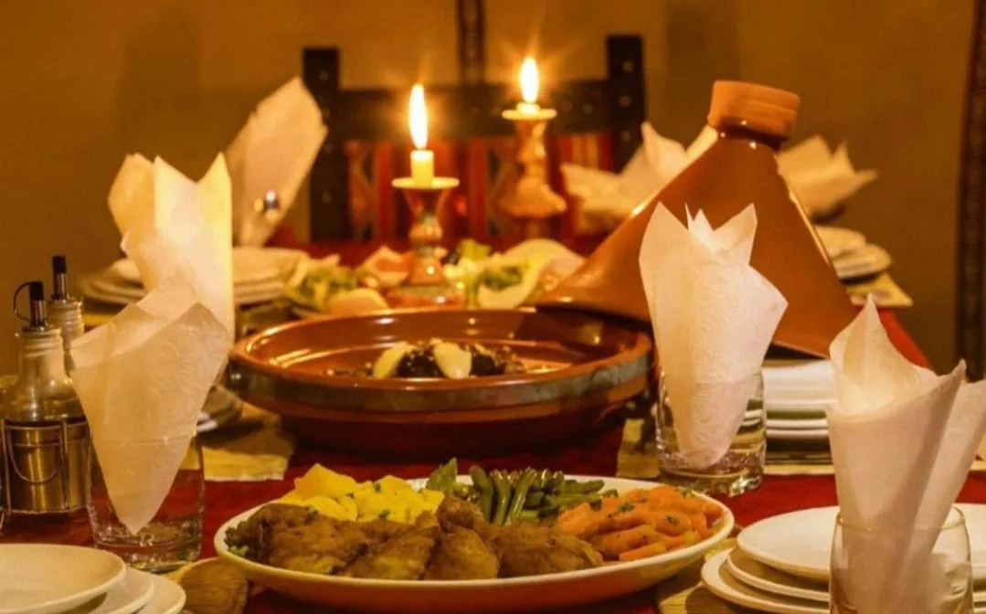 Candlelit dinner setting at Golden Dunes Luxury Camp in Merzouga with traditional dishes and elegant table presentation.