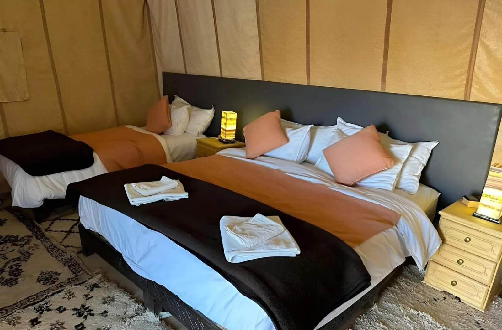 Family suite at Golden Dunes Luxury Camp in Merzouga with multiple beds, bedside lamps, and warm-toned bedding.