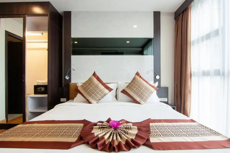Neatly made bedroom at Golden Jomtien Beach Hotel in Pattaya with decorative bedding and bedside lighting.