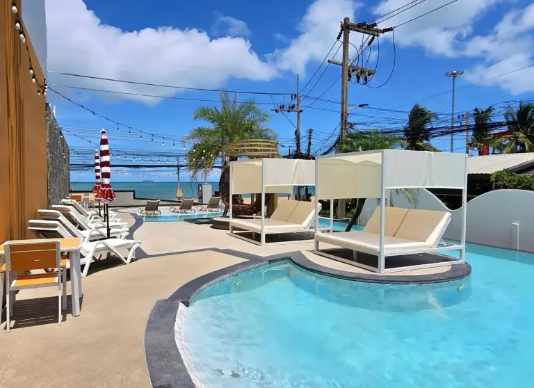 Pool deck at Golden Jomtien Beach Hotel in Pattaya with cabana loungers, sunbeds, and sea views.