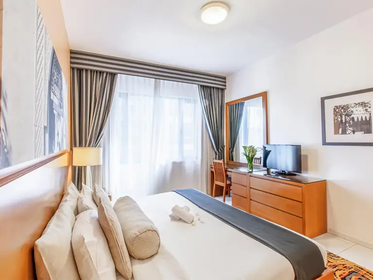 Golden Sands Hotel Apartments Dubai chambre avec grand lit, télévision, commode et fenêtre lumineuse