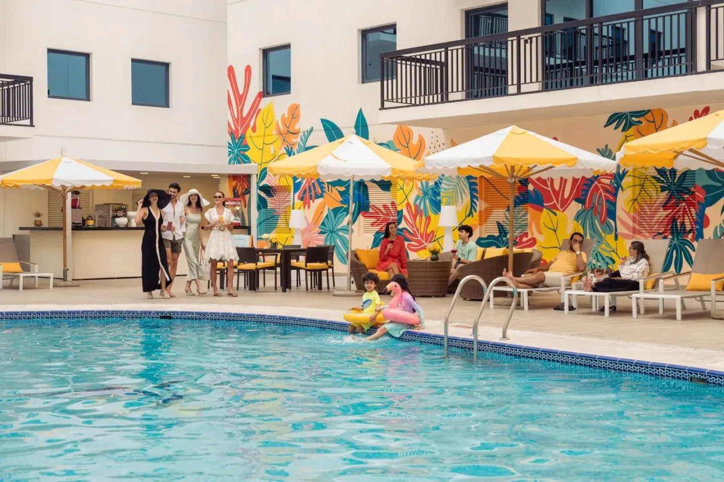 Espace piscine de Golden Sands Suites avec des clients profitant du soleil