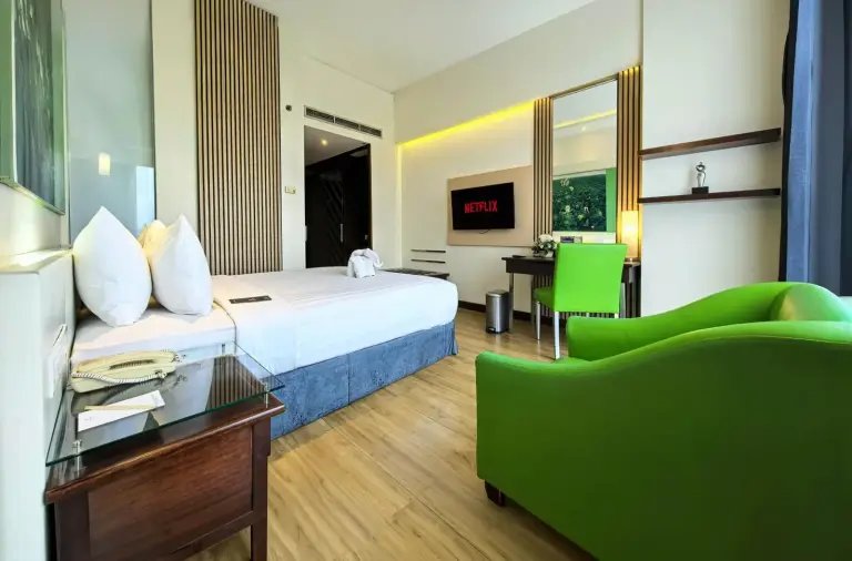 Chambre d’hôtes au Grand Candi Hotel Semarang avec chaise verte, bureau et télévision