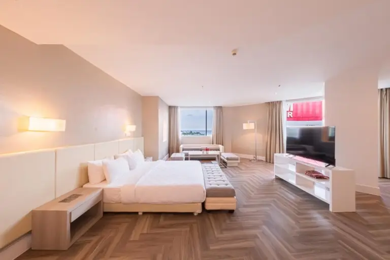 Large bedroom lounge at Grand Jatra Hotel Balikpapan with a bed, armchair, TV, and window view