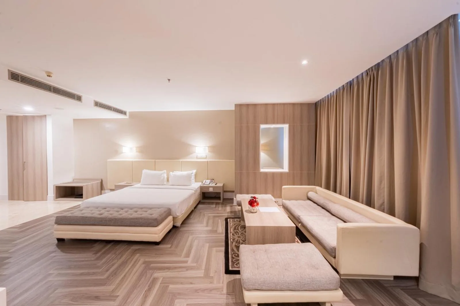 Executive suite at Grand Jatra Hotel Balikpapan with a bed, sofa lounge, and curtains along the window wall