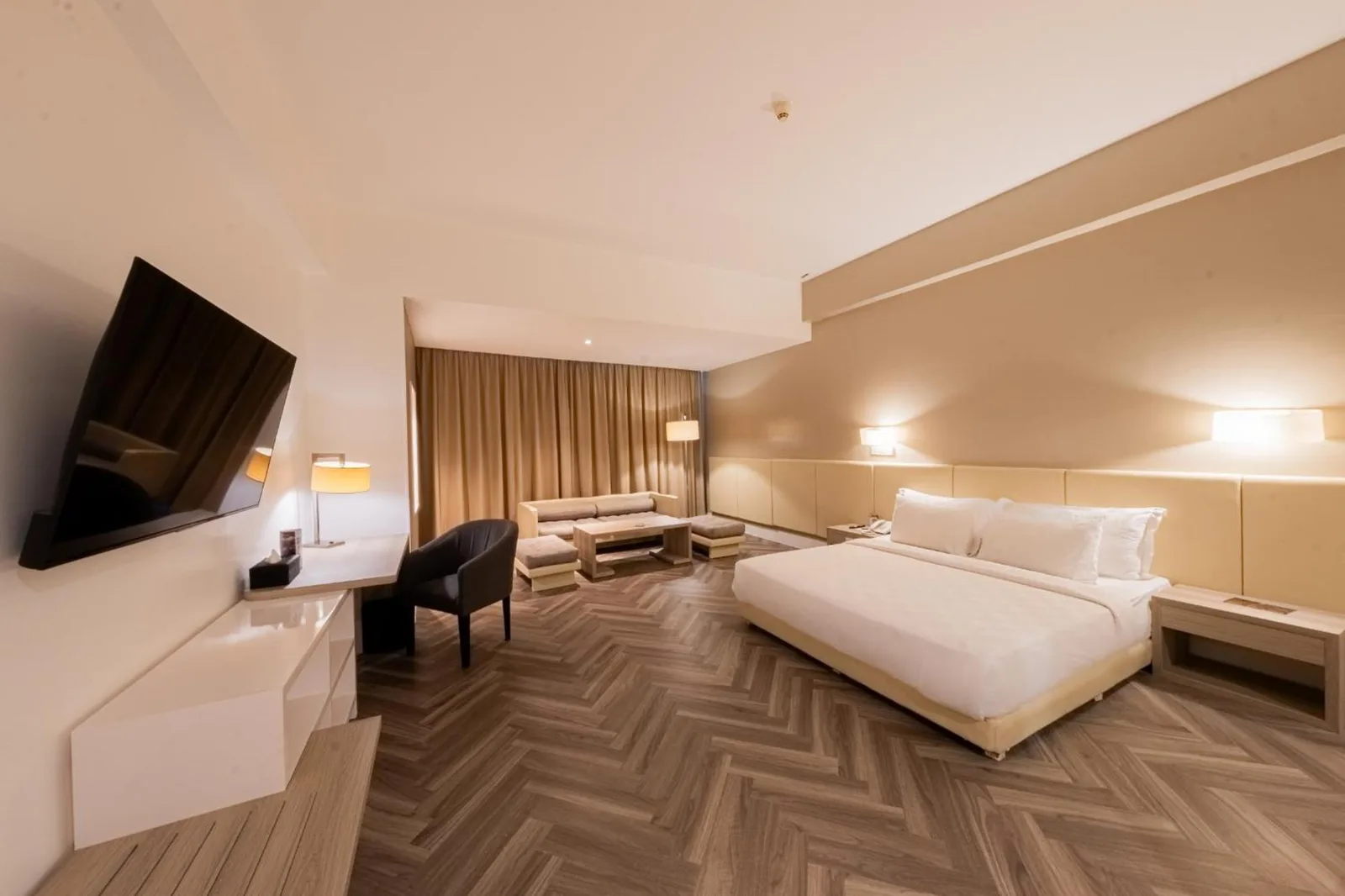 Spacious guest room at Grand Jatra Hotel Balikpapan with a king bed, TV, desk, and seating area