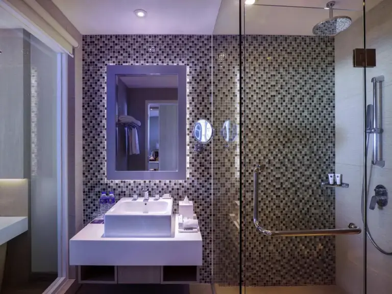 Bathroom at Grand Mercure Bandung Setiabudi in Bandung with mosaic tile wall, sink vanity, and glass shower