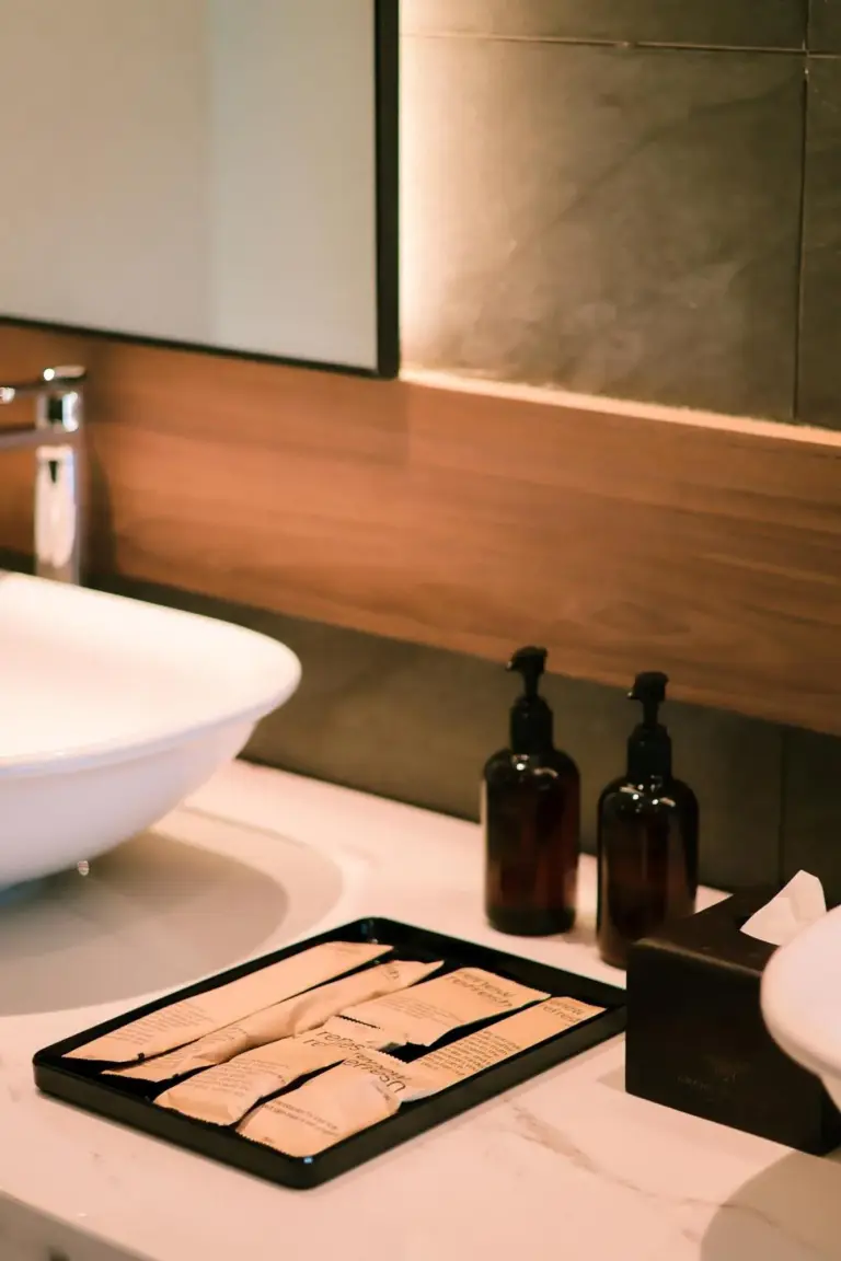 Detalle acogedor junto a la cama en una habitación de huéspedes de Grand Mercure Batam Centre con lámpara y toalla doblada.