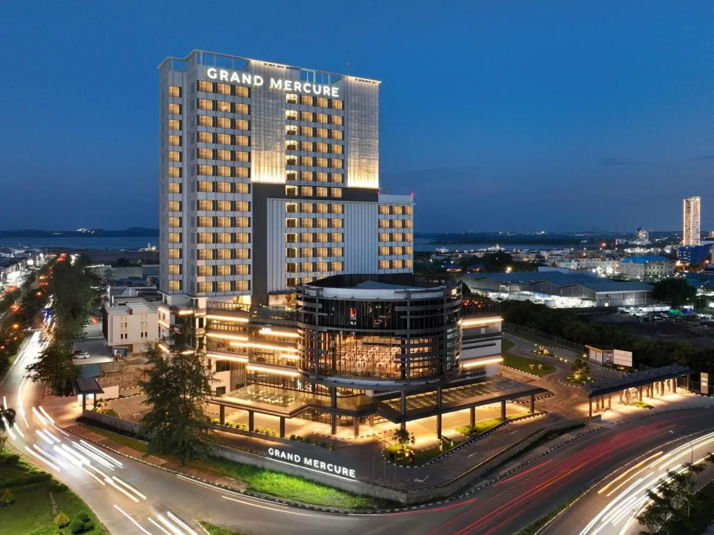 Exterior del hotel Grand Mercure Batam Centre en Batam al atardecer, con torre iluminada y luces de la ciudad.