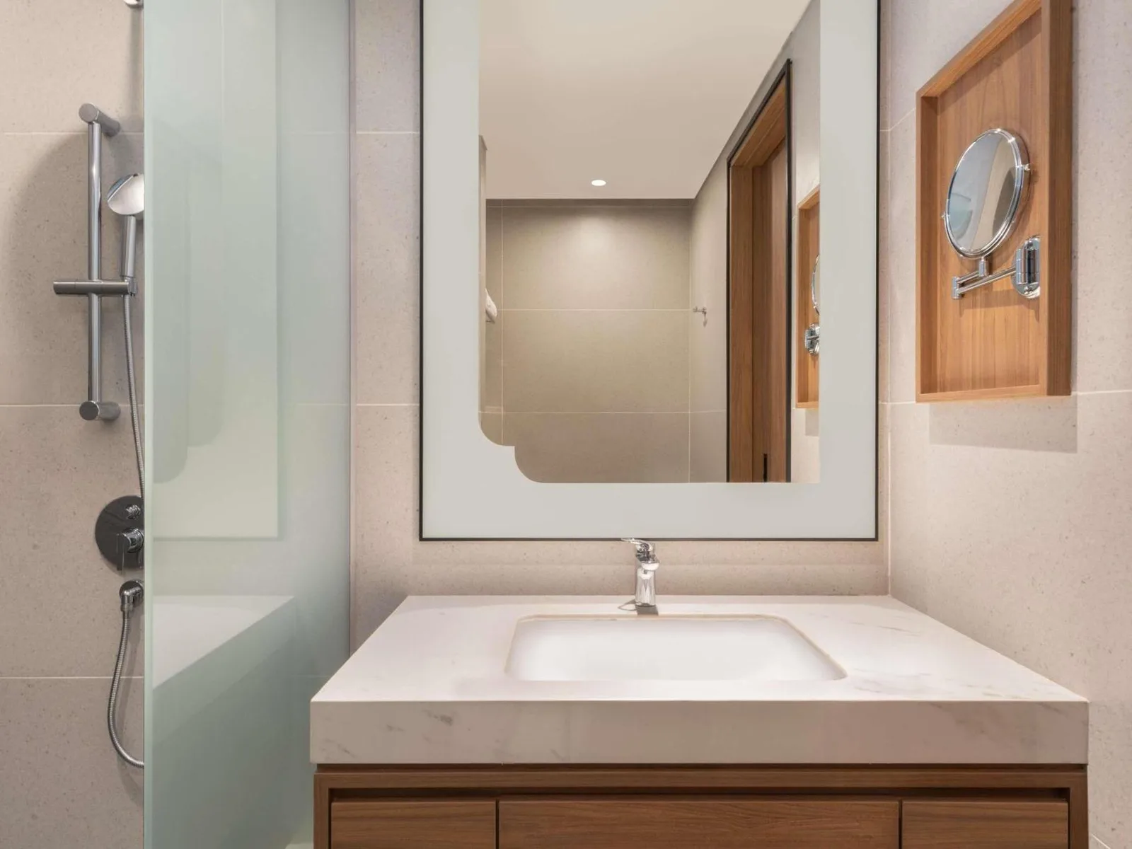 Tocador y zona de ducha en el baño de Grand Mercure Batam Centre con acabados contemporáneos.