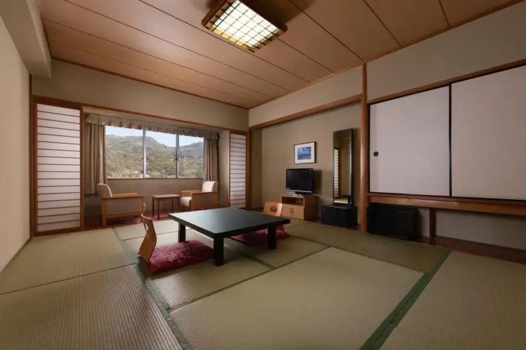 Grand Mercure Beppu Bay Resort & Spa – Hotel in Beppu, Japan – ein Wohnzimmer mit einem Tisch und einem großen Fenster im Grand Mercure Beppu Bay Resort & Spa in Beppu