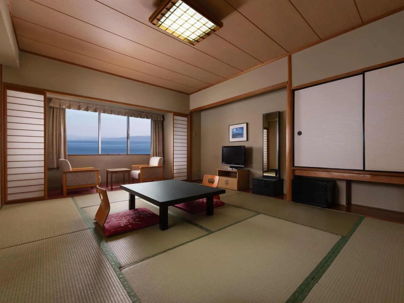 Grand Mercure Beppu Bay Resort & Spa – Hotel in Beppu, Japan – ein Wohnzimmer mit einem Tisch und einem Bildschirm im Grand Mercure Beppu Bay Resort & Spa in Beppu