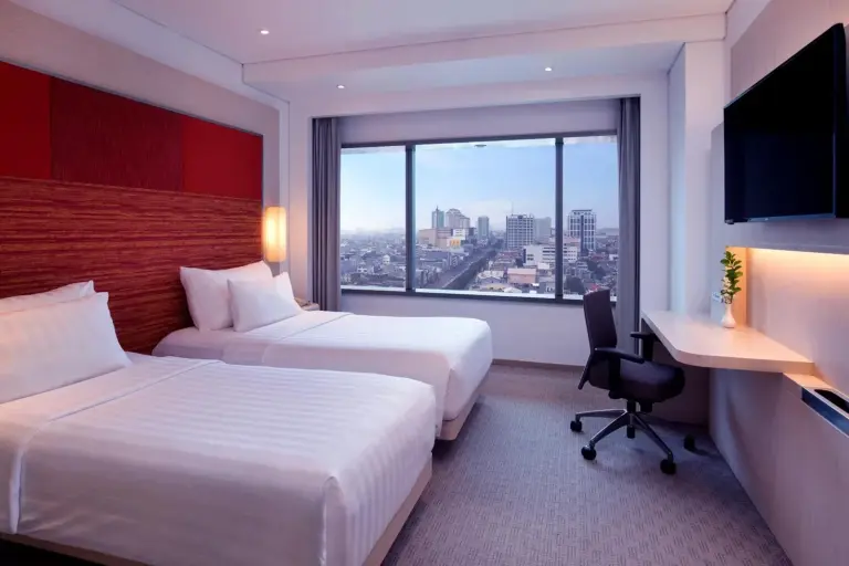 Innenraum eines Zweibettzimmers im Grand Mercure Jakarta Harmoni mit Betten, Schreibtisch, Spiegel und Duschbereich