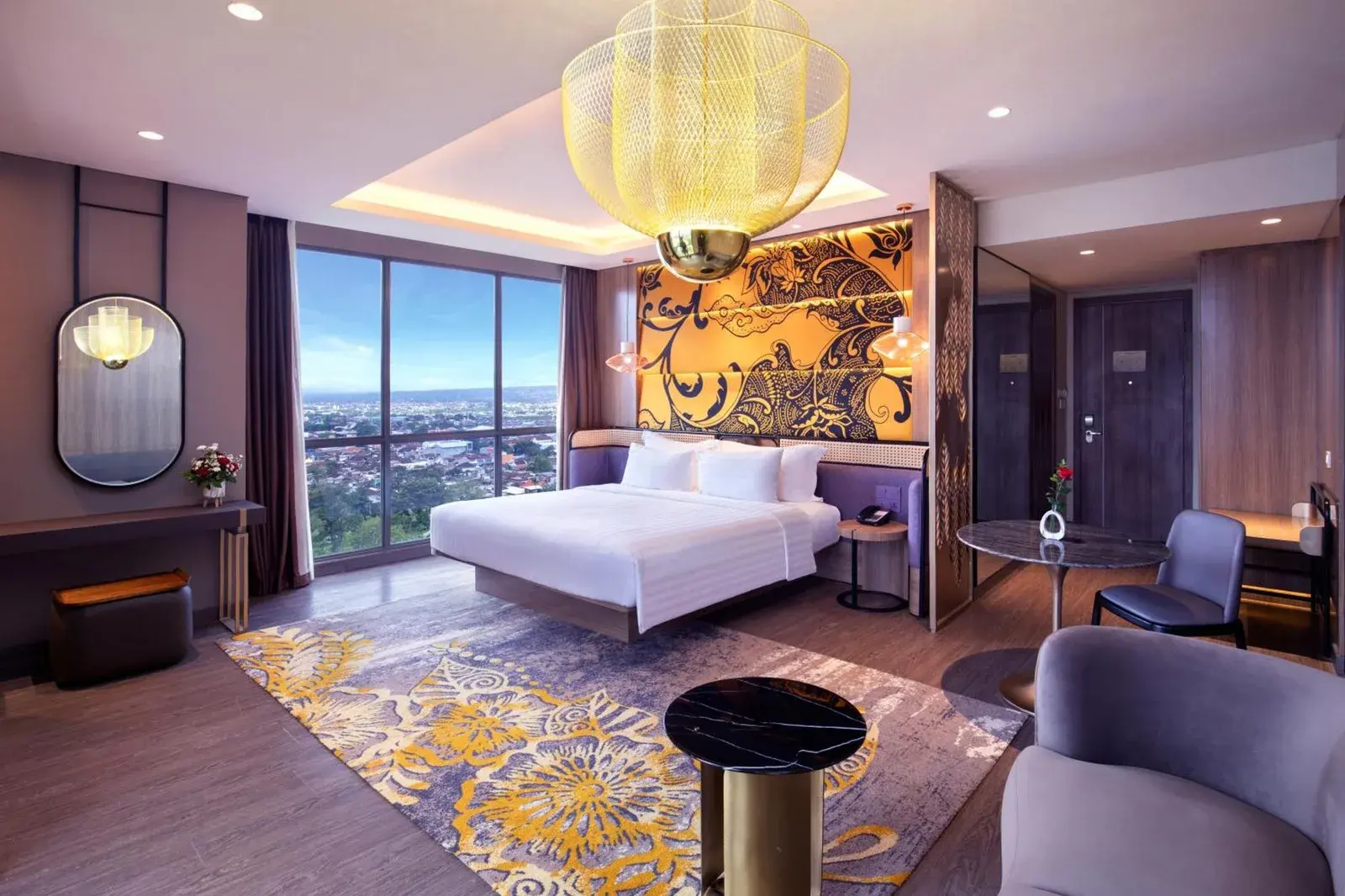 Elegante suite ejecutiva en Grand Mercure Malang Mirama en Malang con cama, zona de estar y panorama urbano