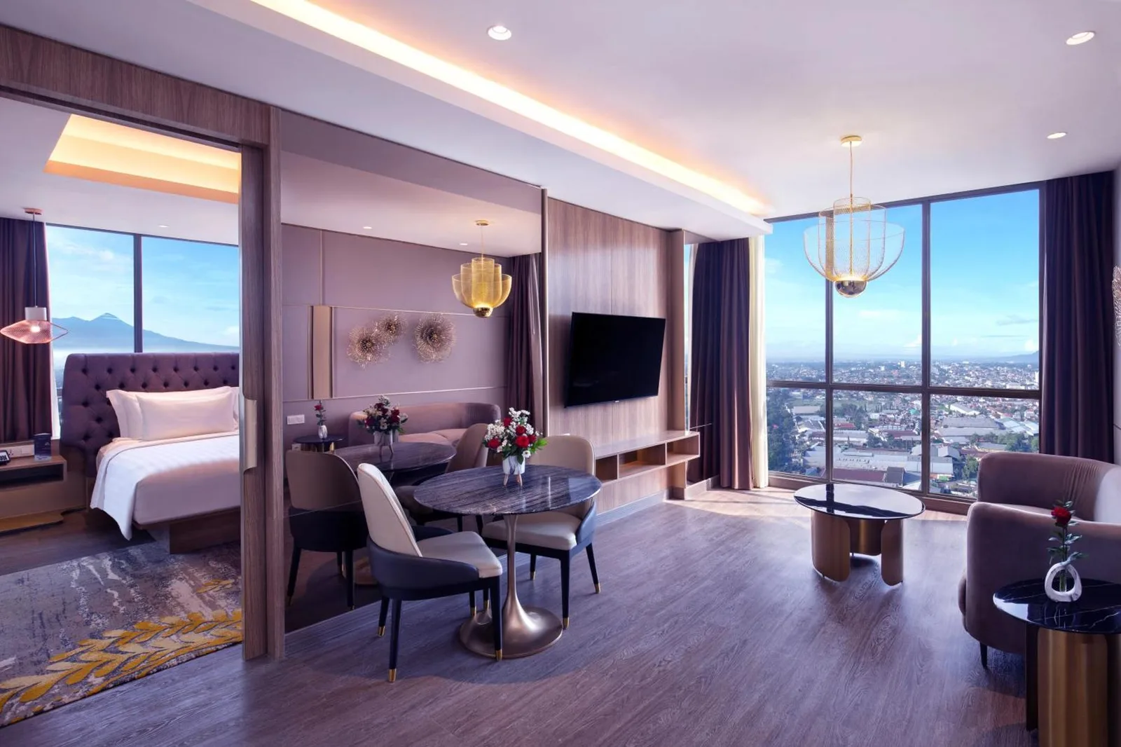Amplia sala de estar de una suite en Grand Mercure Malang Mirama en Malang con mesa de comedor y ventanal panorámico
