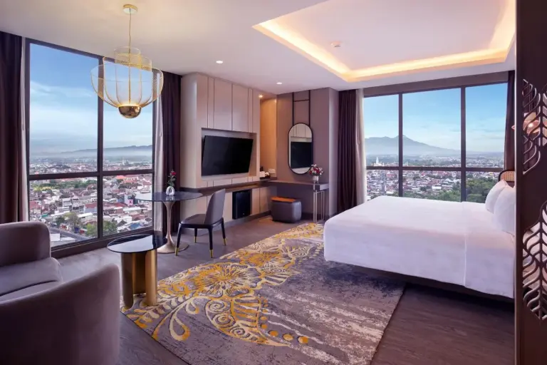 Suite esquinera en Grand Mercure Malang Mirama en Malang con zona de estar, escritorio de trabajo y vistas al skyline