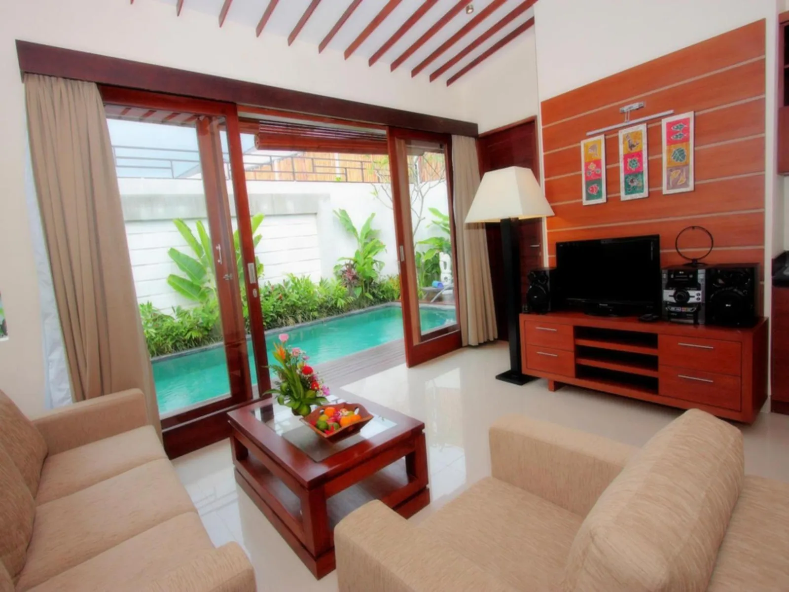 Living room at Grania Bali Villas in Seminyak overlooking the private pool through large glass doors.