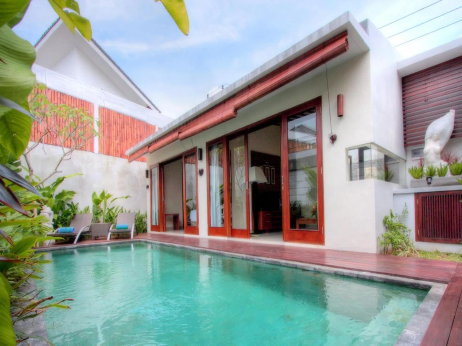 Private pool villa exterior at Grania Bali Villas in Seminyak with glass doors and pool deck.