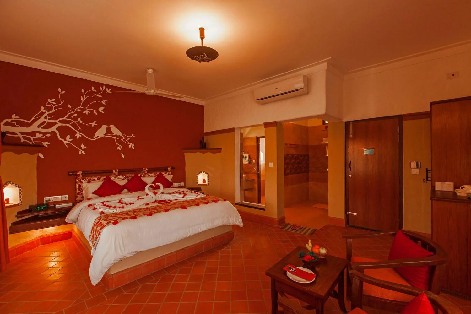 Chambre romantiquement décorée à l’hôtel Green Park Chitwan à Sauraha avec un lit king-size et un éclairage chaleureux.