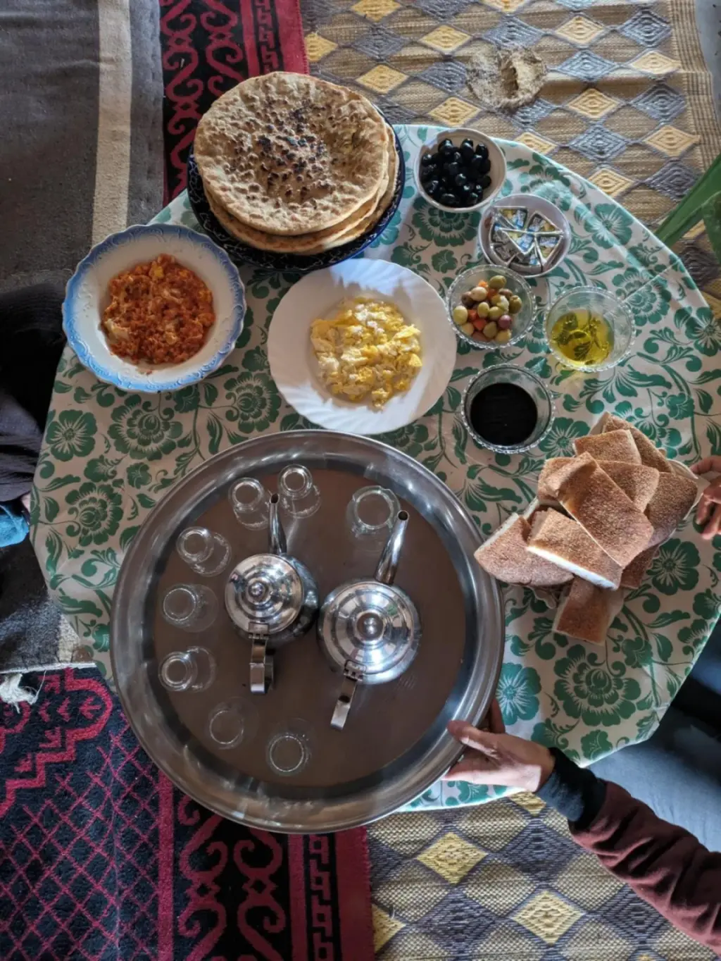 Frühstückstisch im Guest House Nomad Life in Merzouga mit Tee, Fladenbrot, Eiern, Oliven und marokkanischen Beilagen.