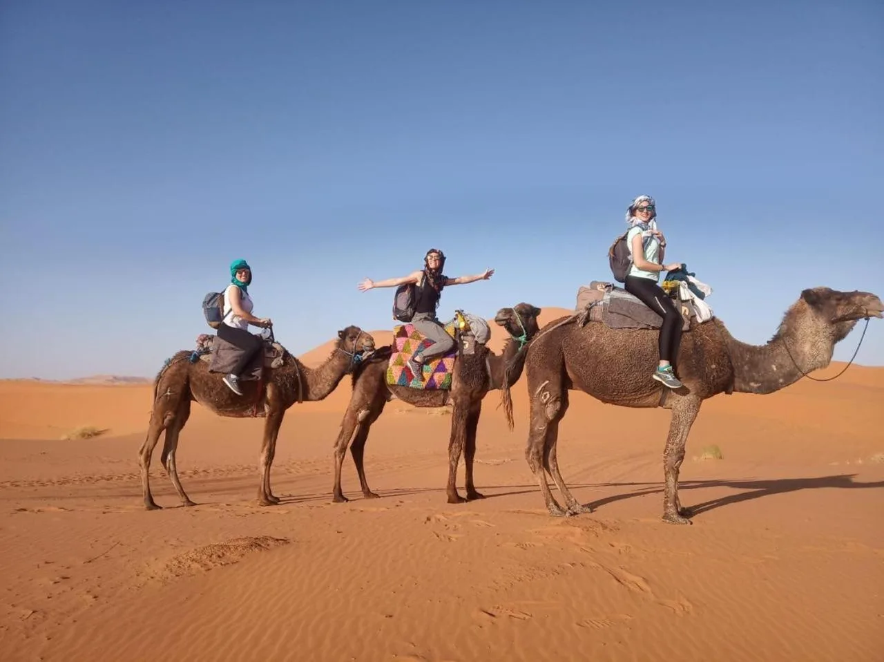 Tourists riding camels in the Sahara Desert near Guests House in Merzouga.