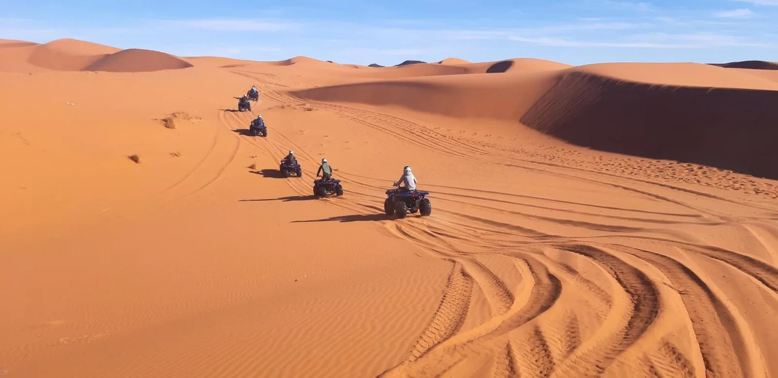 Quad bikes riding across the sand dunes near Guests House in Merzouga in the Sahara Desert.