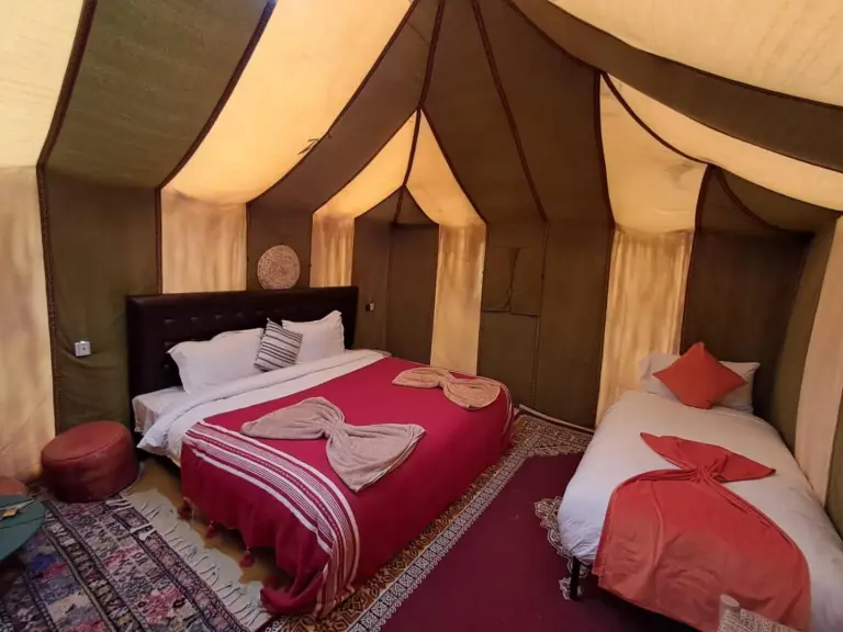 a bedroom with two beds and a dress on at Hassan desert camp in Merzouga