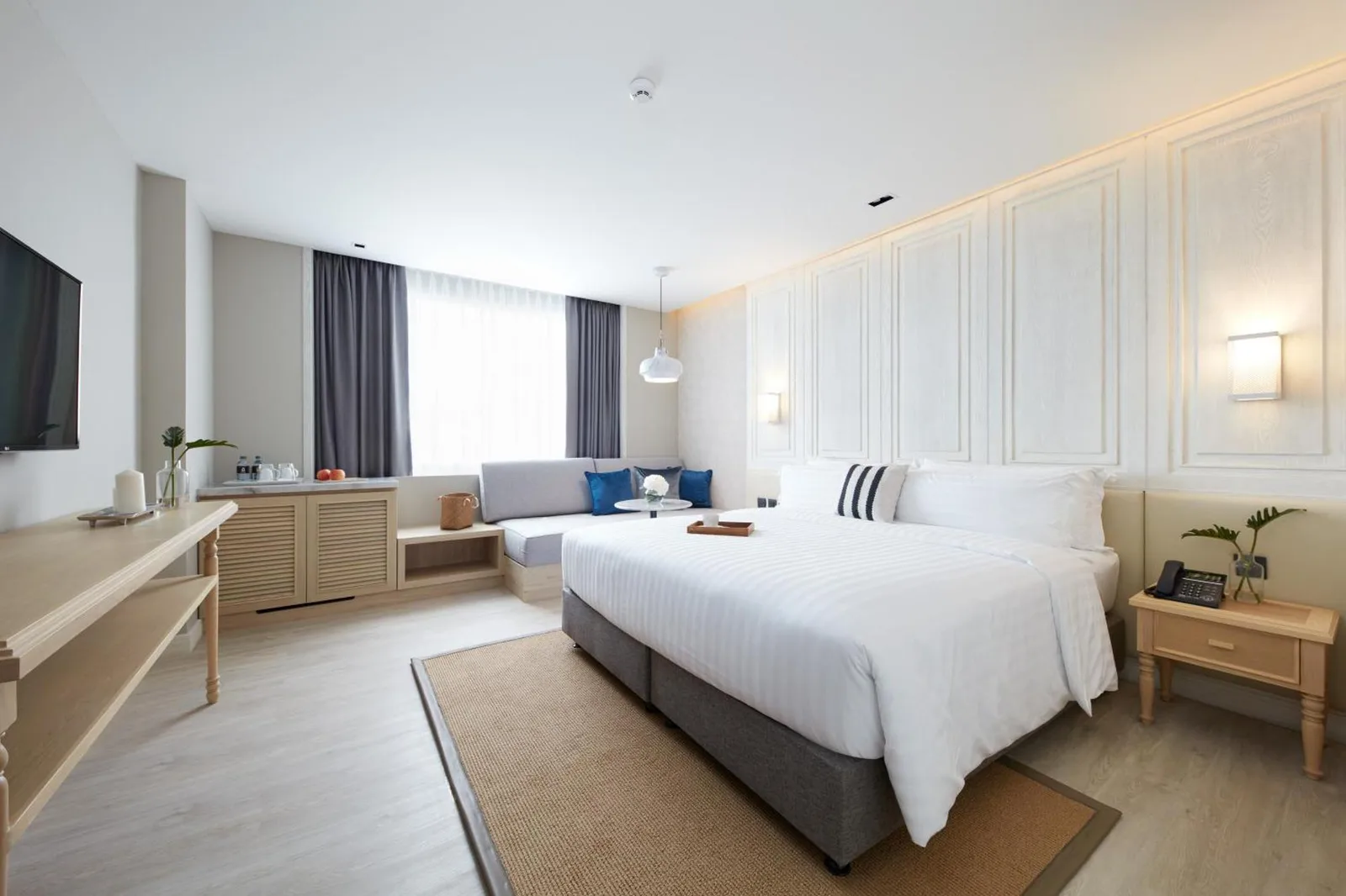 King bedroom at Health Land Resort & Spa Pattaya with large bed, sofa, and elegant wall paneling