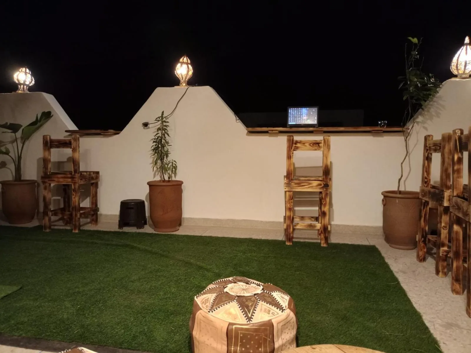 Rooftop terrace at Heaven Surf Camp in Agadir with artificial grass, wooden tables, and night lighting