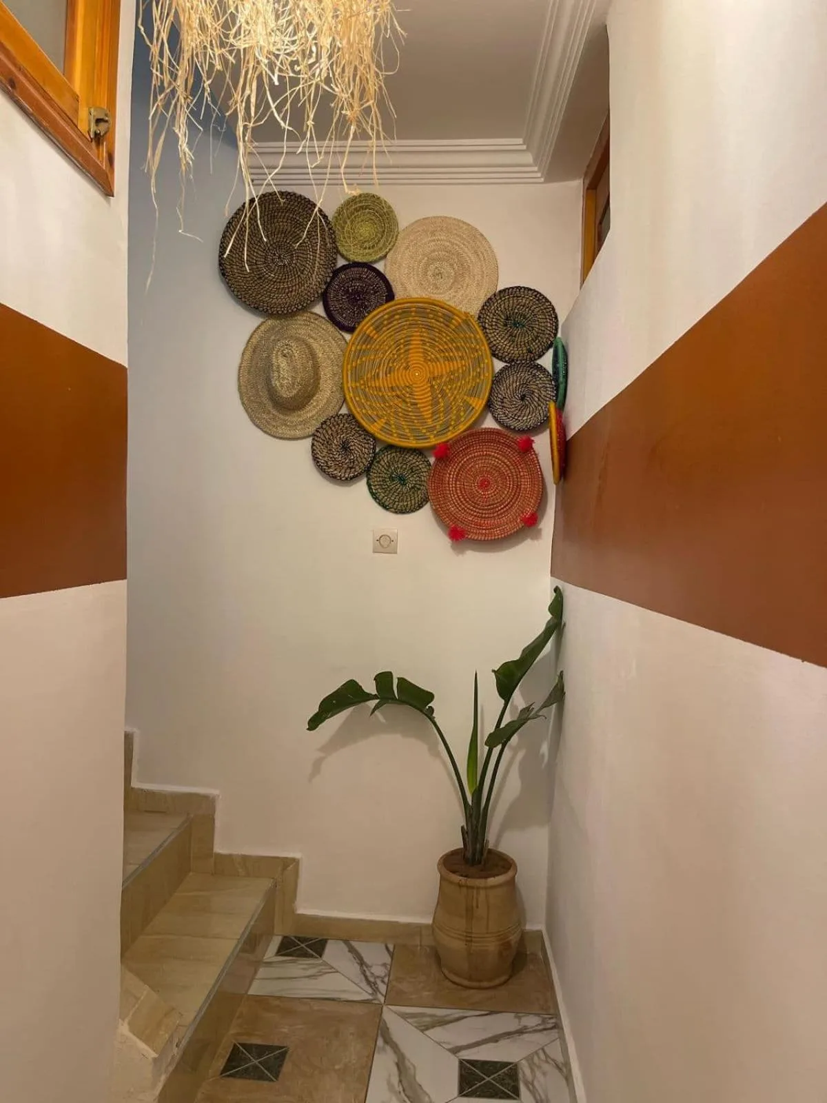Stair landing at Heaven Surf Camp in Agadir decorated with woven wall art and a potted plant