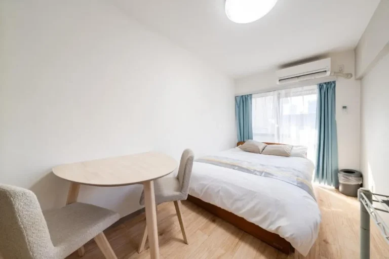 Habitación minimalista en un hotel de Tokyo con una cama y mesa de comedor.