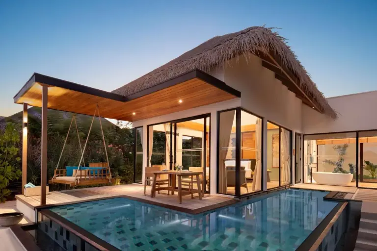 Vista nocturna de una villa de lujo con piscina privada en Hilton Maldives Amingiri Resort & Spa.