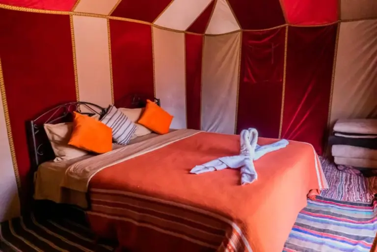 Double bed tent room at Holiday Desert Camp in Merzouga with orange pillows and traditional desert tent walls