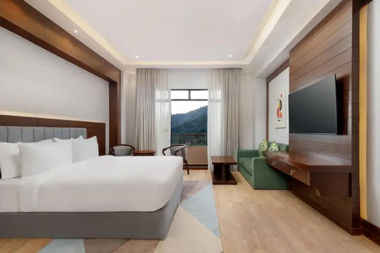 Spacious guest room at Holiday Inn Resort Kathmandu Budhanilkantha by IHG with seating area, TV, and mountain view balcony.