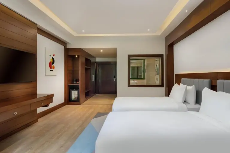 Bright twin room at Holiday Inn Resort Kathmandu Budhanilkantha by IHG with large window, green hill view, and modern furnishings.