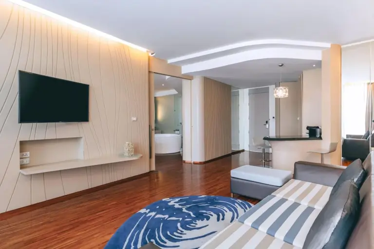 Zona de estar moderna en Hotel Baraquda Heeton Pattaya by Compass Hospitality con sofá, TV y suelo de madera