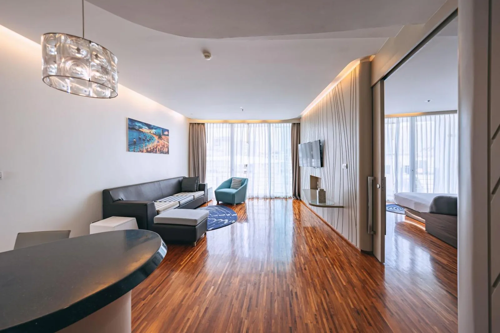 Zona de estar de suite de planta abierta en Hotel Baraquda Heeton Pattaya by Compass Hospitality con mobiliario moderno