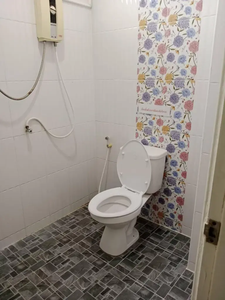 Badezimmer im Boonsuk Mansion in Ubon Ratchathani mit Toilette, Dusche und Fliesen mit Blumenmotiv