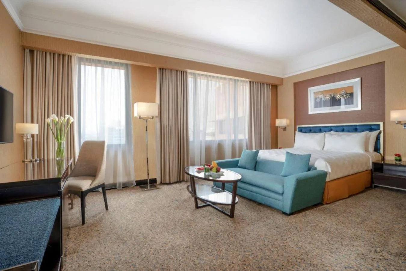 Spacious suite room at Hotel Ciputra Semarang with sofa, bed, desk, and large windows