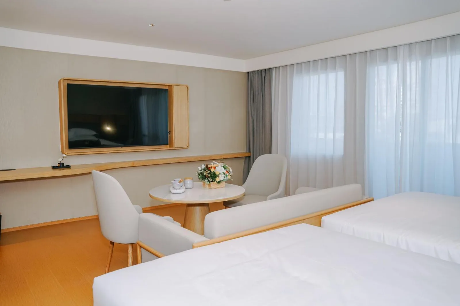 Guest room seating area at Bangkok Oriental Hotel in Bangkok with small table, chairs, and TV by the window.
