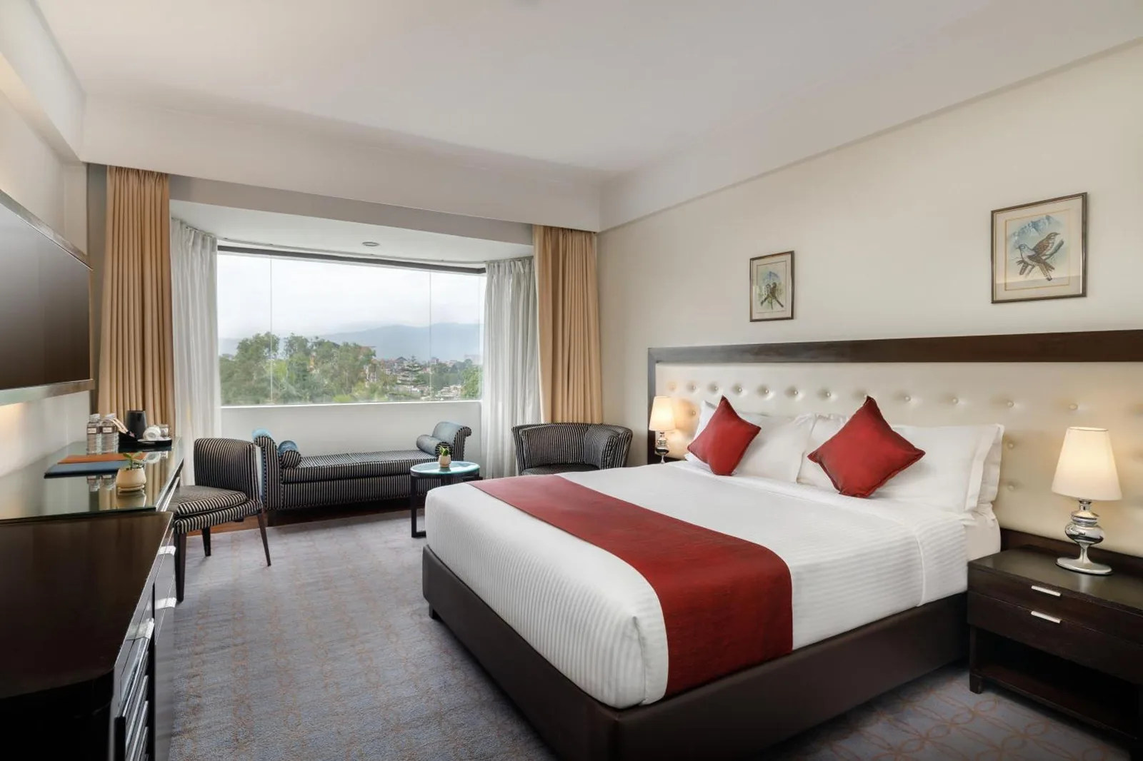Chambre Deluxe à Hotel Himalaya Kathmandu avec un lit king-size, un coin salon et une grande fenêtre avec vue.