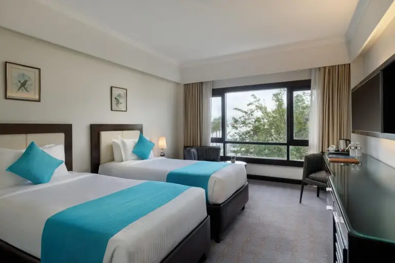Chambre twin à Hotel Himalaya Kathmandu avec deux lits, des touches bleues et une grande fenêtre.