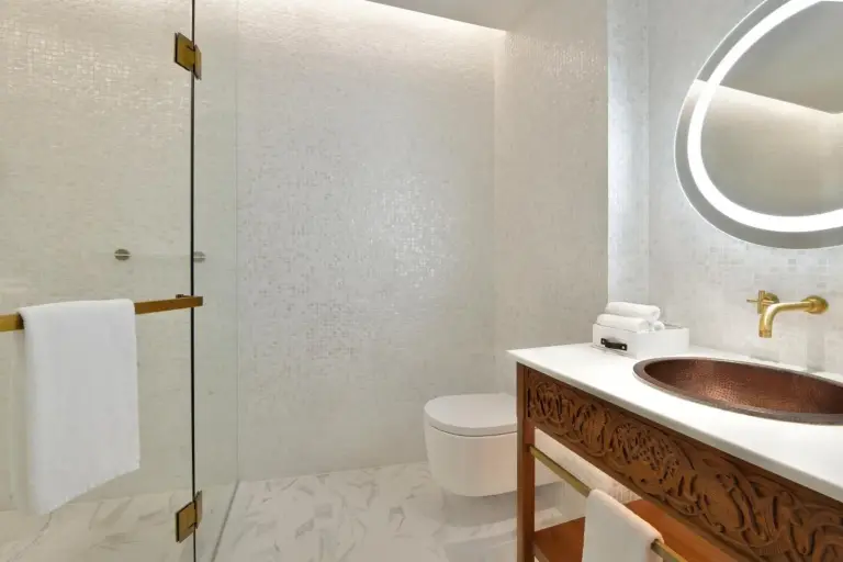 Salle de bains moderne à Hotel Indigo Dubai Downtown by IHG à Dubai avec douche vitrée, lavabo cuivré et miroir éclairé